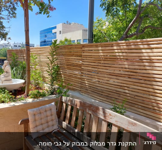 גדר עץ במרפסת עם צמחייה ופסל